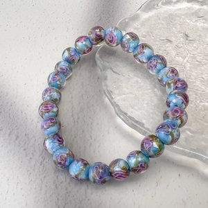 Vue détaillée d'un bracelet en perles de verre bleu clair avec rose rose et paillettes