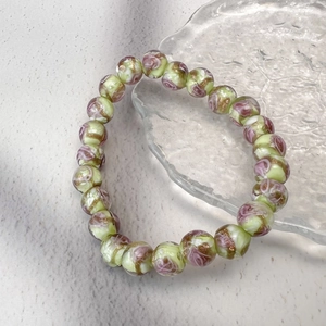 Gros plan de perles de verre florales pastel avec accents dorés sur bracelet élastique