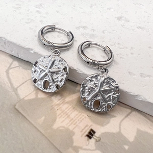 Detailed view of silver hoop earrings with textured starfish relief coin pendant