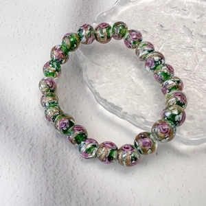Détail macro de perles en verre avec motifs roses roses et feuilles d'or sur bracelet
