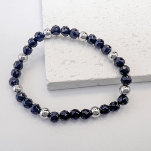 Detail of beaded bracelet with dark faceted glass and silver-tone metal spacers