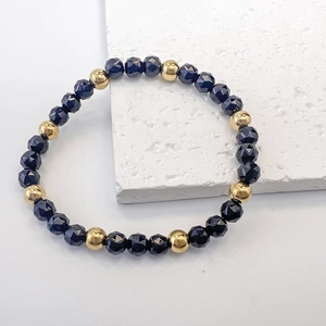 Detail of 6mm dark blue faceted beads and gold metal beads on an elastic stretch bracelet