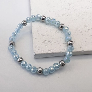 Macro detail of 6mm light blue faceted glass beads and polished steel beads on stretch bracelet