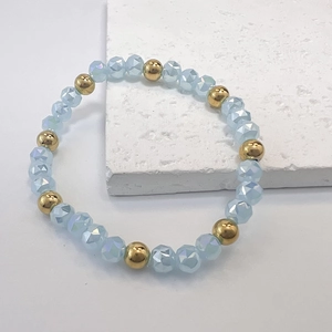 Close-up of light blue faceted beads and golden metal beads on a beaded stretch bracelet