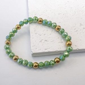Detail of light green faceted glass beads and polished gold metal spacers on stretch bracelet