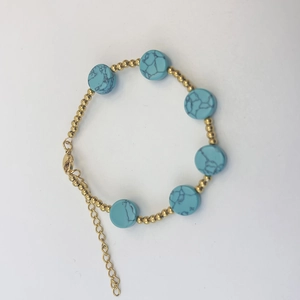 Détail du bracelet perlé en or 18 carats orné de charmes en pierre naturelle turquoise