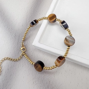 Détail des perles en acier doré 18K et pierres œil de tigre avec fermoir mousqueton