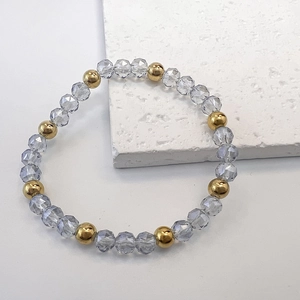 Macro shot of 6mm light blue faceted glass and gold steel beads on stretch bracelet
