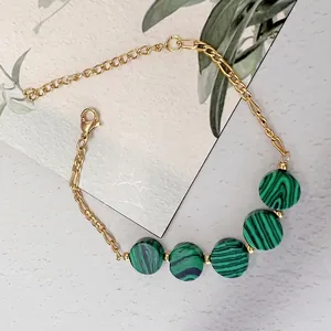 Close-up of gold stainless steel bracelet featuring five round green malachite stones