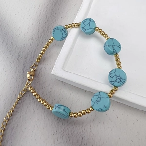 Gros plan de perles turquoise et de billes en acier inoxydable doré 18K sur un bracelet