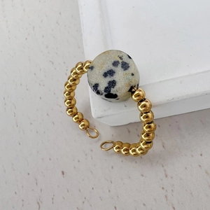Detail of 18K gold-plated beaded ring with natural spotted stone on a white background