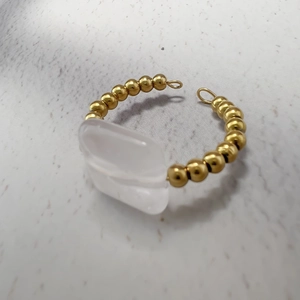 Macro view of a 18K gold stainless steel ring with beaded band and rectangular white stone