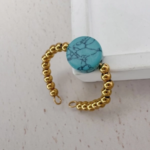 Detail of 18K gold beaded band ring featuring a round turquoise natural stone setting