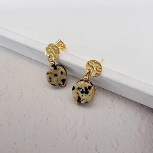 Close-up of bohemian earrings with hammered gold metal and spotted natural stone drops