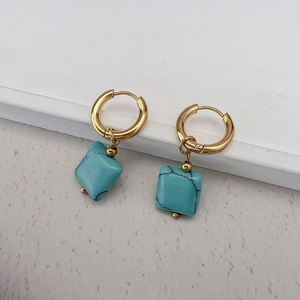 Detail of 18K gold stainless steel earrings with square faux turquoise pendants and stone texture