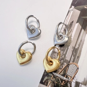 Poliertes Set aus Herzohrringen in Gold und Silber auf modernem Mode-Magazin-Hintergrund