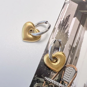 Detail von zweifarbigen Herzohrringen mit polierter Silber- und Goldmetalloberfläche