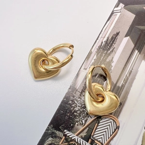 Detail von goldenen Herzohrringen auf einem stilvollen Magazin mit minimalistischem Look