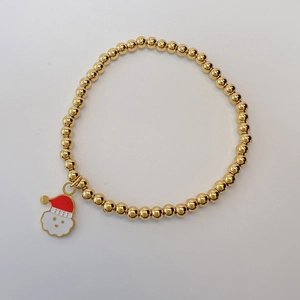 Detailed view of a gold beaded bracelet featuring a festive Santa Claus charm drop