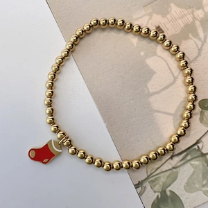 Close-up of golden beaded elastic bracelet featuring a red Christmas stocking charm