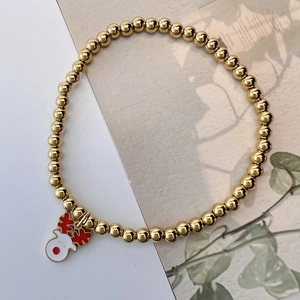 Detail of Christmas beaded bracelet with golden beads and a colorful reindeer charm
