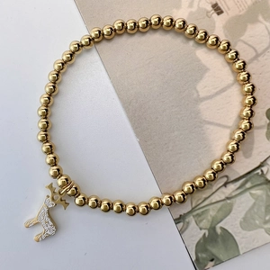 Close-up of golden stainless steel beaded bracelet with elk charm on a soft background