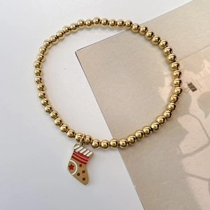 Detailed close-up of golden 4mm bead bracelet with a red and gold Christmas stocking charm