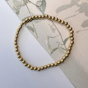 Macro detail of 4mm golden round beaded elastic bracelet with high polished mirror finish