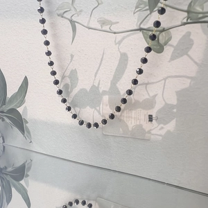 Detailed view of long necklace featuring faceted black glass beads with gold link accents