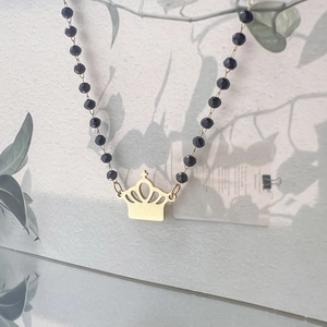 Detail of vintage gold crown pendant with black multifaceted beaded chain and elegant design