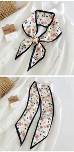 Détail d'un foulard long en soie à fleurs noué sur un col de chemise blanche chic