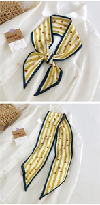 Détail d'un long foulard à rayures avec motifs cœurs rouges et bordure marine sur une chemise