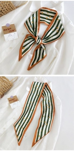 Détail d'un foulard twilly en soie avec motif de cœur vert et bords orange sur chemise