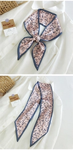 Gros plan d'un foulard en soie rose à fleurs avec bordure bleue noué sur une chemise