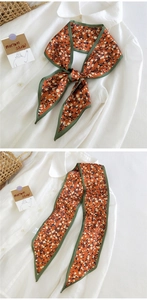 Détail d'un foulard en soie à fleurs noué sur une chemise blanche, orange et brun