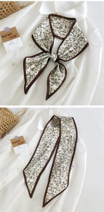 Gros plan d'un foulard étroit à fleurs crème avec bordure marron noué sur une chemise