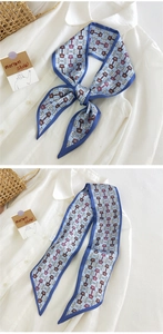 Détail d'un foulard en soie noué en boucle sur chemise blanche à motif mors de cheval