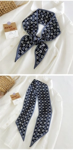 Détail d'un twilly bleu marine à motif chaîne noué en nœud papillon sur un col de chemise