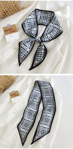 Détail d'un foulard en soie à motif pied-de-poule noué sur une chemise blanche chic