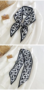 Détail d'un foulard étroit à motif vache noué en ruban sur un col de chemise blanche