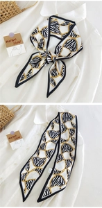 Détail d'un foulard twilly à motif zébré et chaîne dorée sur une chemise blanche