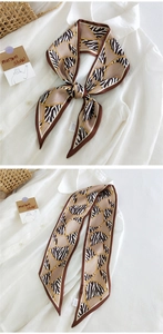 Détail macro du foulard en soie à motif zébré et chaînes noué en un nœud