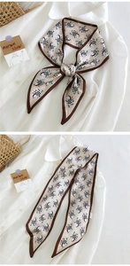 Détail d'un foulard en soie à motif zèbre noué en nœud sur une chemise blanche