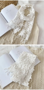 Détail d'une écharpe en dentelle florale blanche avec pompons et motifs au crochet
