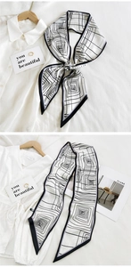 Detail showing elegant black and white geometric silk scarf tied on a white shirt
