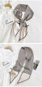 Detail of thin silk scarf with houndstooth pattern and black borders on white shirt