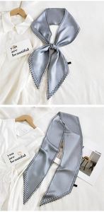 Detail view of a long grey-blue silk scarf with houndstooth pattern used as a necktie