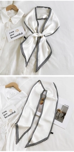 Detail of white silk scarf with houndstooth borders showing elegant bow tying on a shirt
