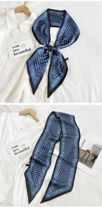 Detailed close-up of blue paisley silk twilly scarf styled with white shirt and magazines