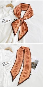 Macro detail of silk-like long scarf showing orange paisley and geometric tile patterns